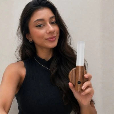 Mulher segurando a Arandela Magno mostrando o design moderno e a iluminação aconchegante sem fio