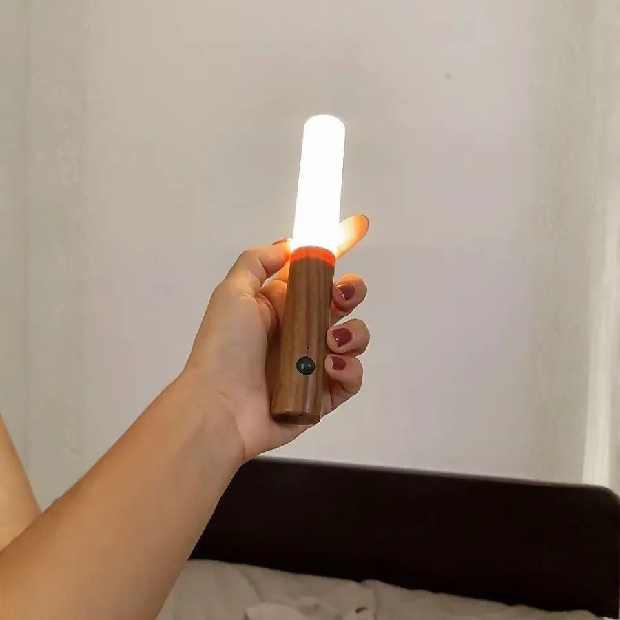 Pessoa segurando a Arandela Magno acesa mostrando iluminação portátil e aconchegante para uso noturno