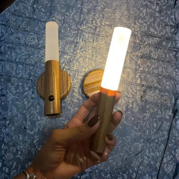 Pessoa segurando a Arandela Magno enquanto a base permanece fixada na parede mostrando o sistema magnético sem fio